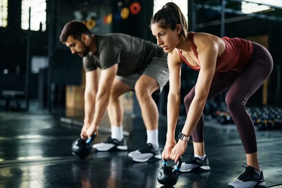 A man and woman performing kettlebell deadlifts together during a training session at Catalyst Training Co gym in Randwick.